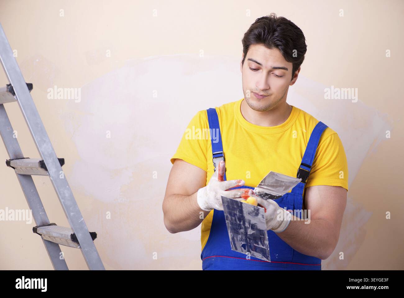 Young contractor employee applying plaster on wall Stock Photo