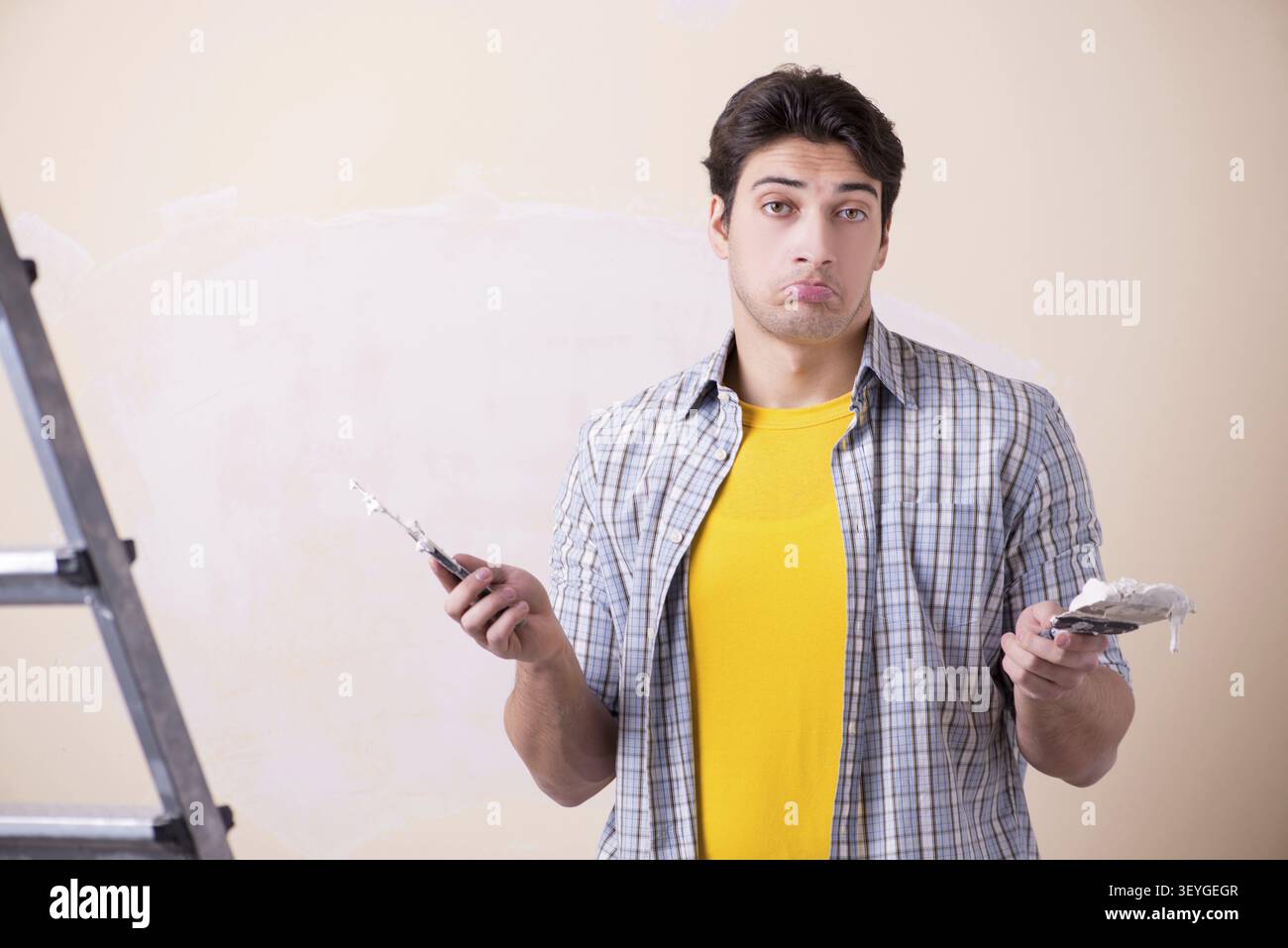 Young man applying plaster on wall at home Stock Photo