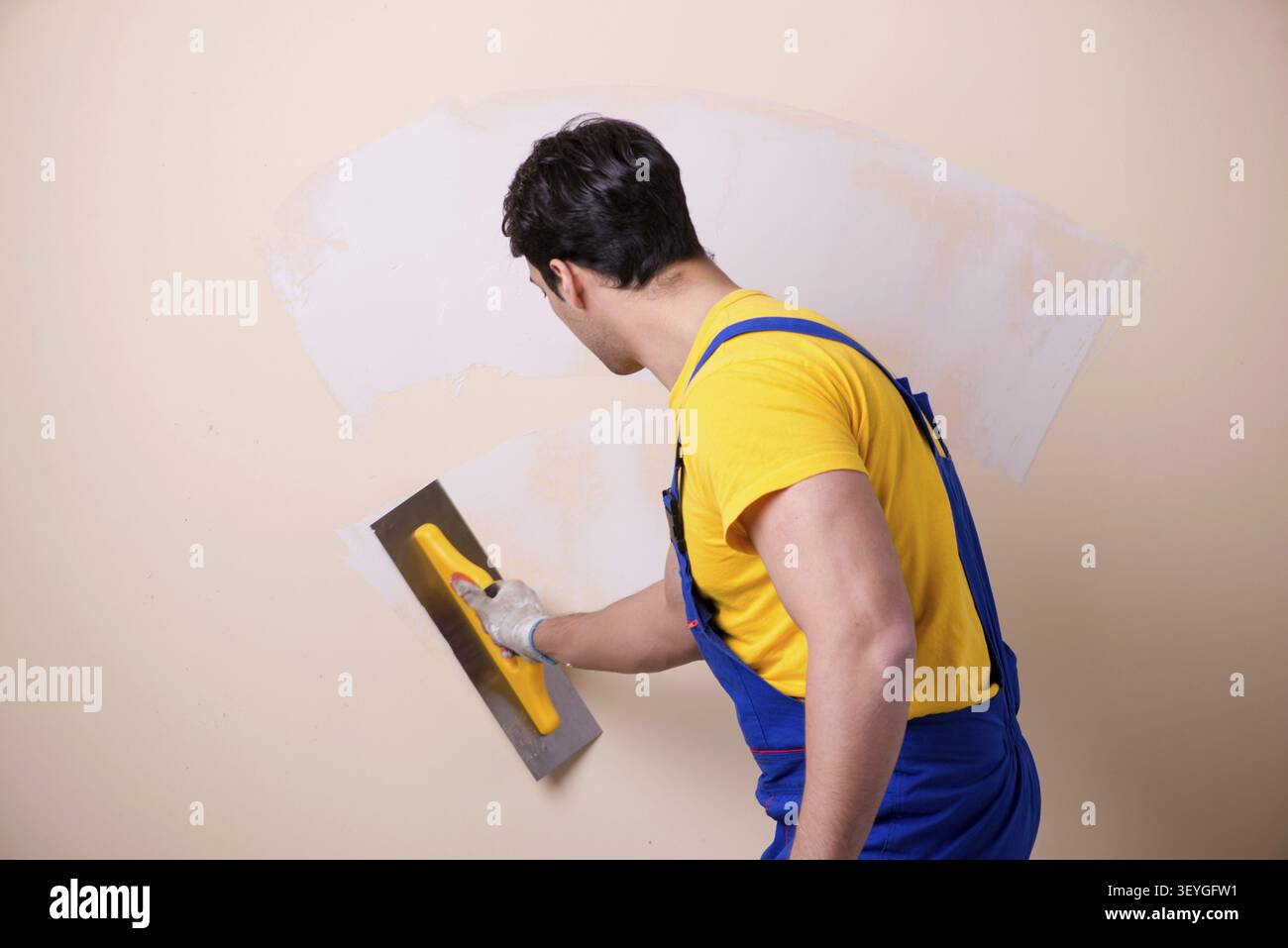 Young contractor employee applying plaster on wall Stock Photo