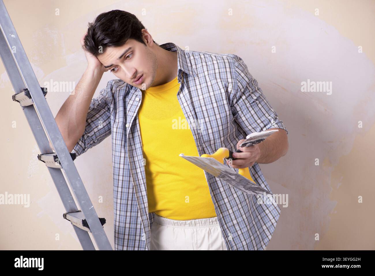 Young man applying plaster on wall at home Stock Photo