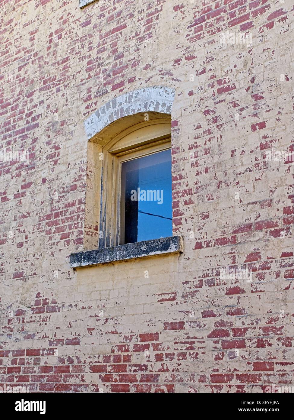 Window in arched window frame of old brick wall Stock Photo