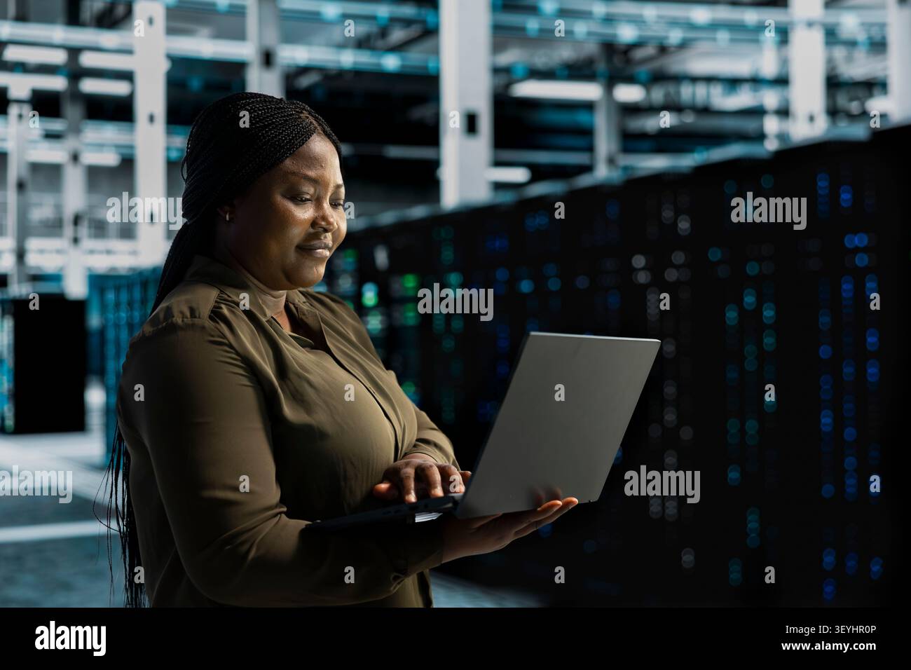 Cheerful systems engineer does maintenance on server facility electronics processing large datasets. Stock Photo