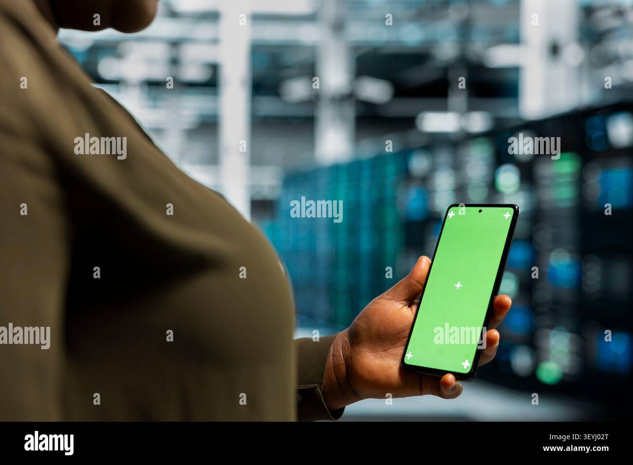 Data center programmer works with a chroma key smartphone, using an editable screen to review performance data. Stock Photo