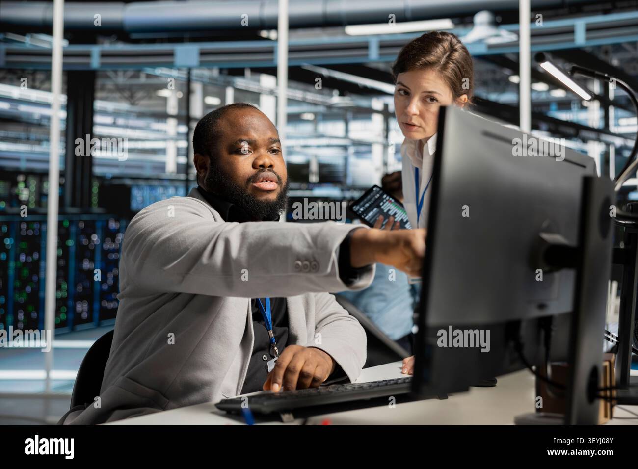 Data center manager uses a computer to run diagnostics, update servers and check infrastructure performance. Stock Photo