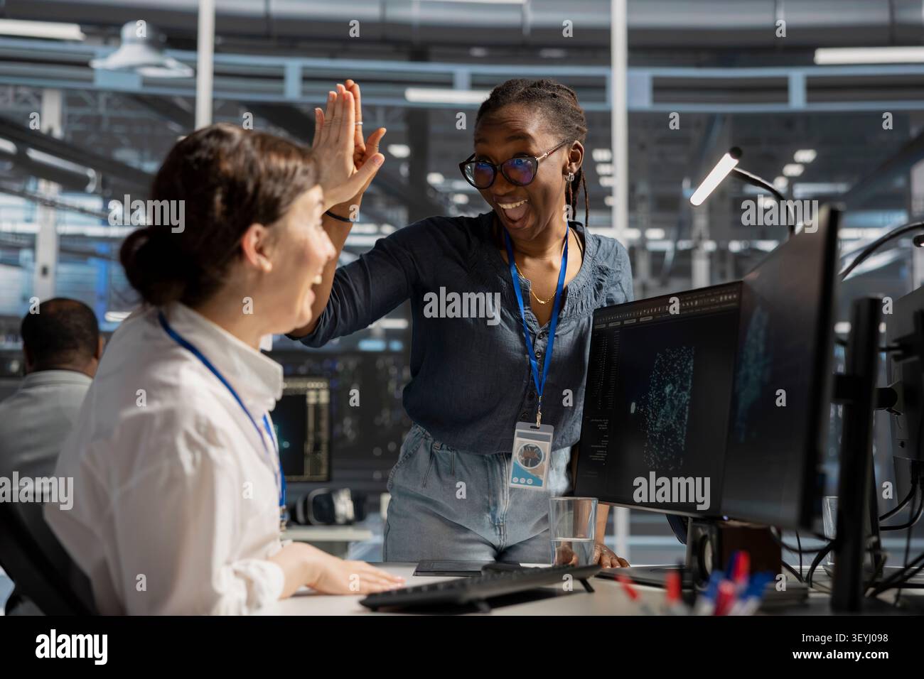 Delighted data center colleagues share a high five after improving system efficiency and completing AI implementation. Stock Photo