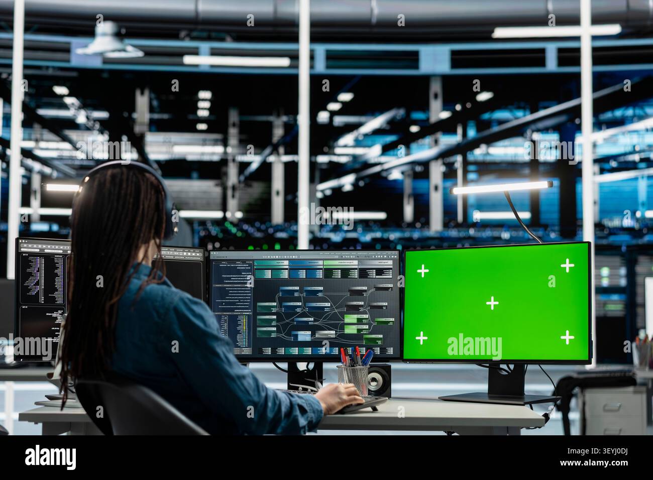 Data center programmer works with a chroma key computer, using an editable screen to review performance data. Stock Photo