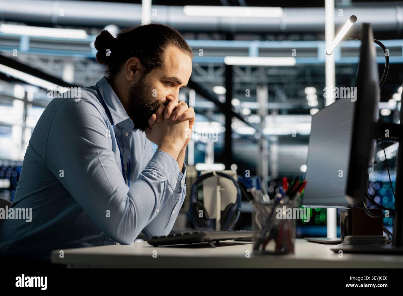Data center engineer uses a computer to update server software, supporting reliable infrastructure operations. Stock Photo