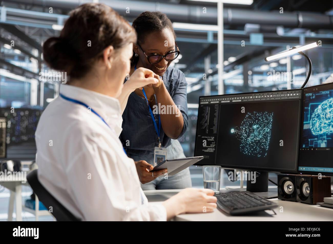 Smiling data center team works with digital devices while reviewing systems, scripts and server infrastructure. Stock Photo