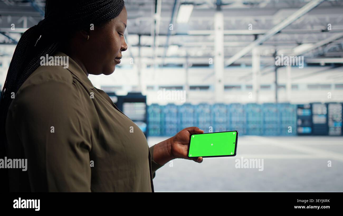 Data center administrator works with a chroma key smartphone, using an editable screen to watch a technical tutorial. Stock Photo