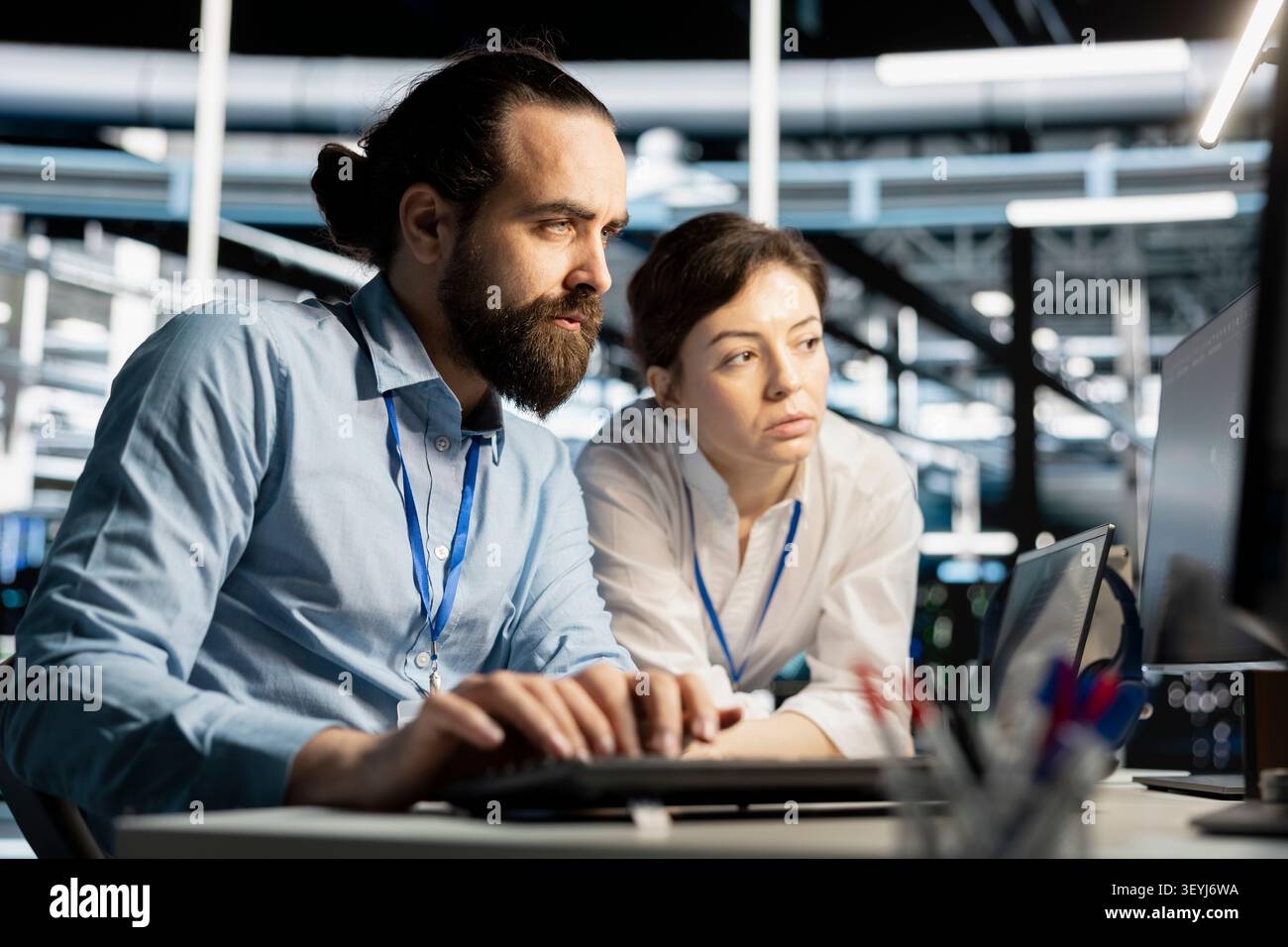 Data center colleagues collaborate on coding and AI automation scripts while reviewing server infrastructure together. Stock Photo