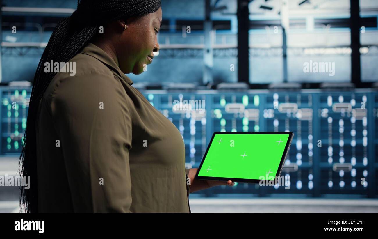 Data center administrator works with a chroma key tablet, using an editable screen to manage technical tasks. Stock Photo