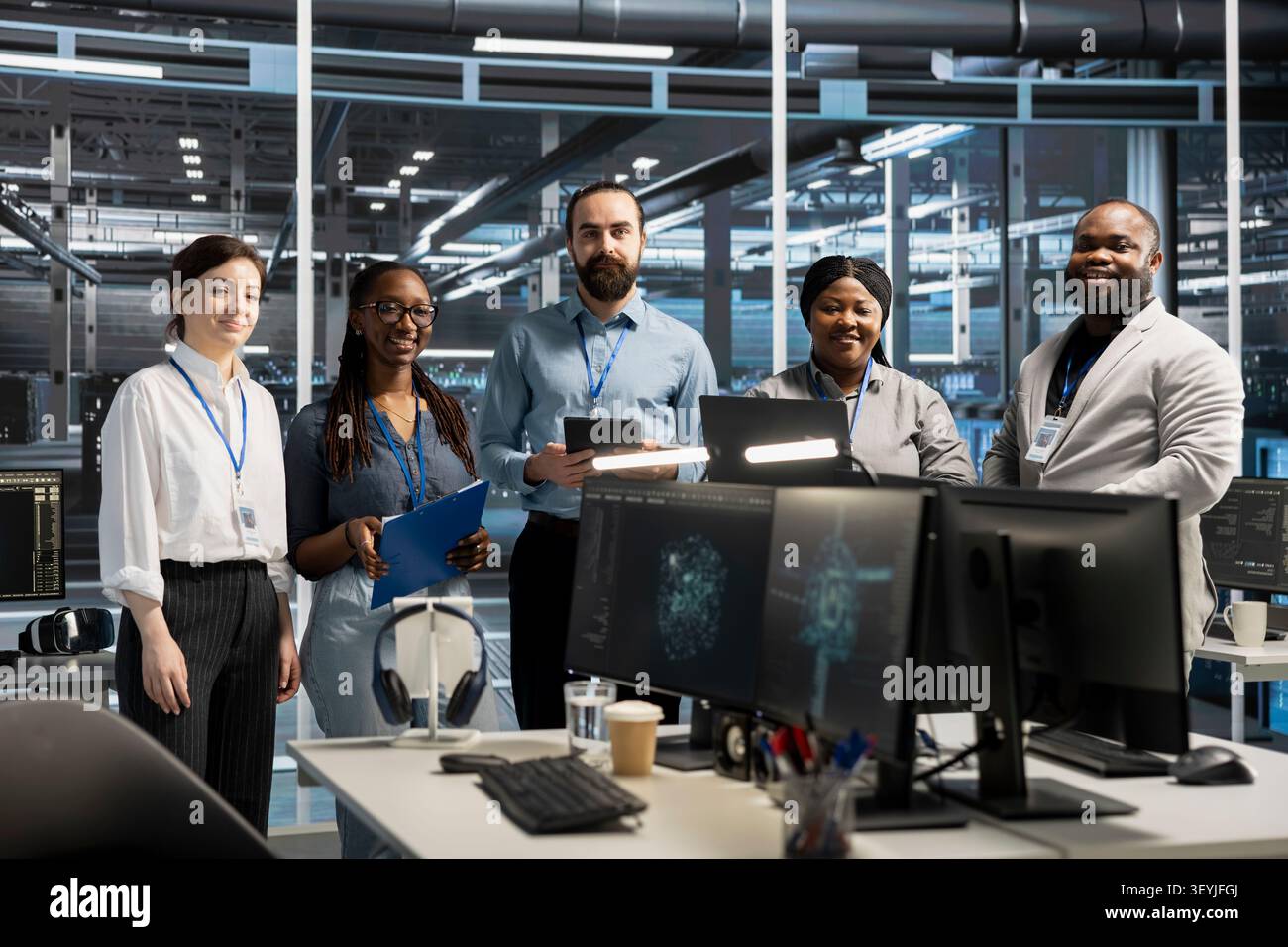 Cheerful engineering team working in server environment, analyzing data. Happy teamworking employees examining infrastructure in server facility, supporting system integrity and security. Stock Photo