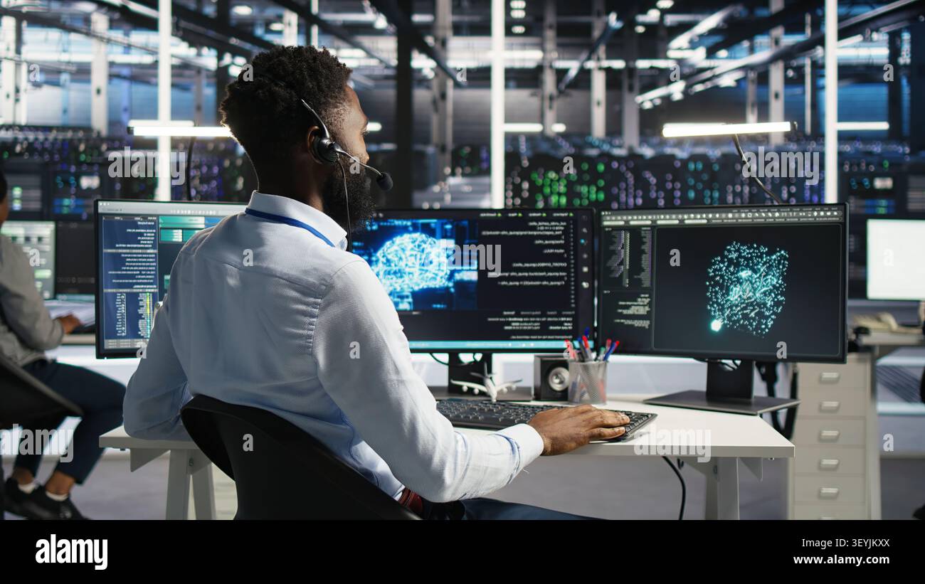 Server room employee talking in headset mic, coordinating technicians setting up hardware for AI deployment. Stock Photo