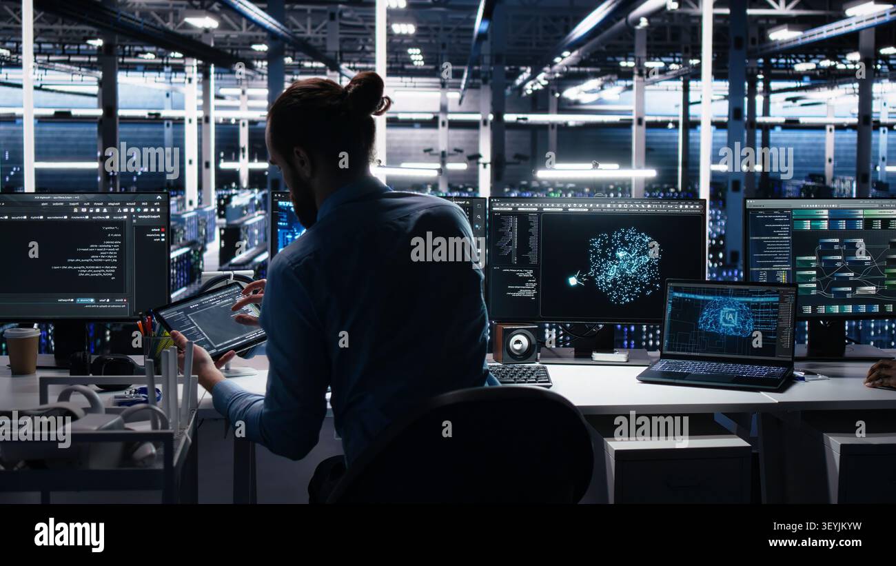 Administrator programs on a laptop in a data center with generative AI assistance. Stock Photo