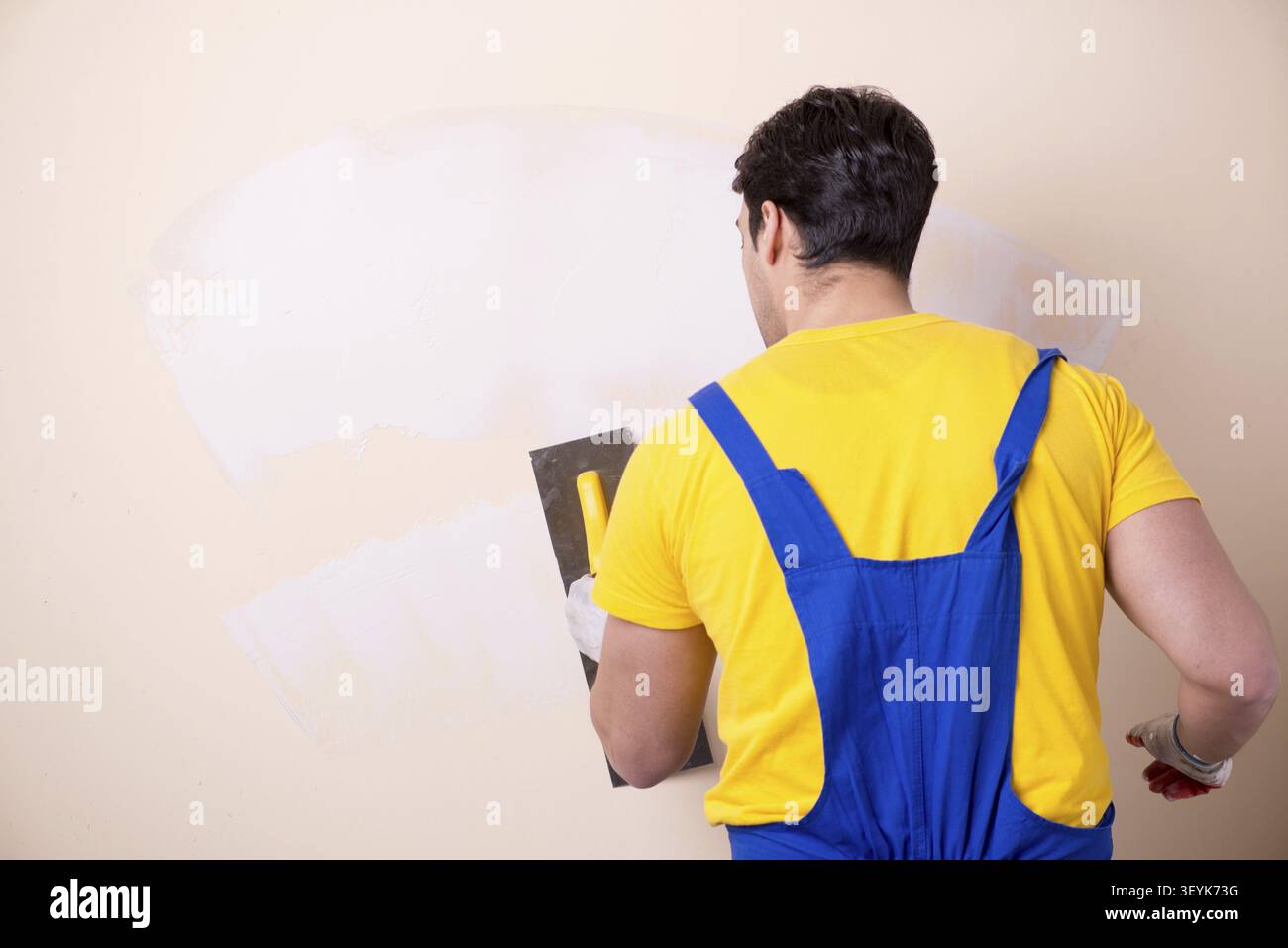 Young contractor employee applying plaster on wall Stock Photo