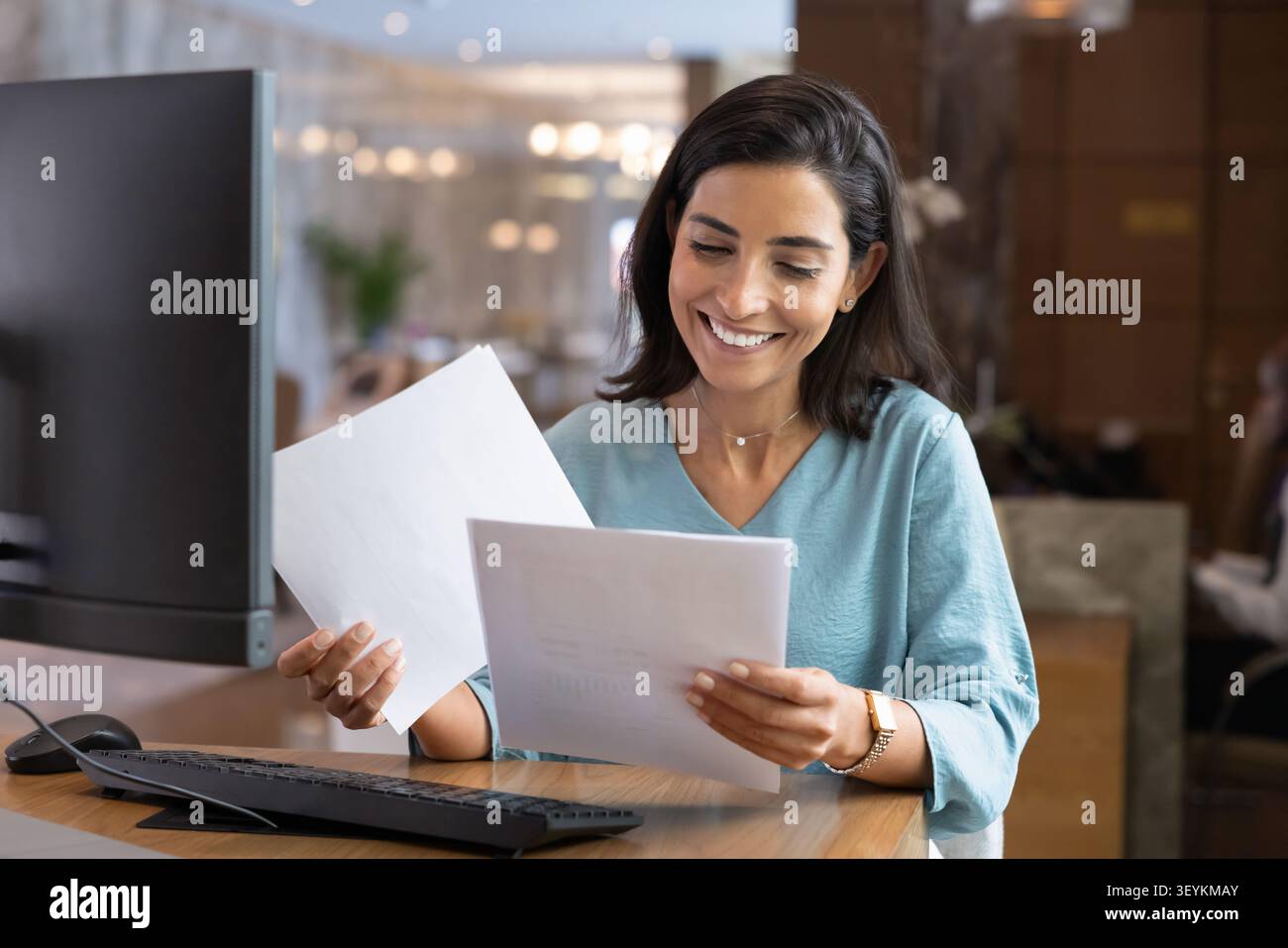 Hotel receptionist reviewing documents at front desk Stock Photo