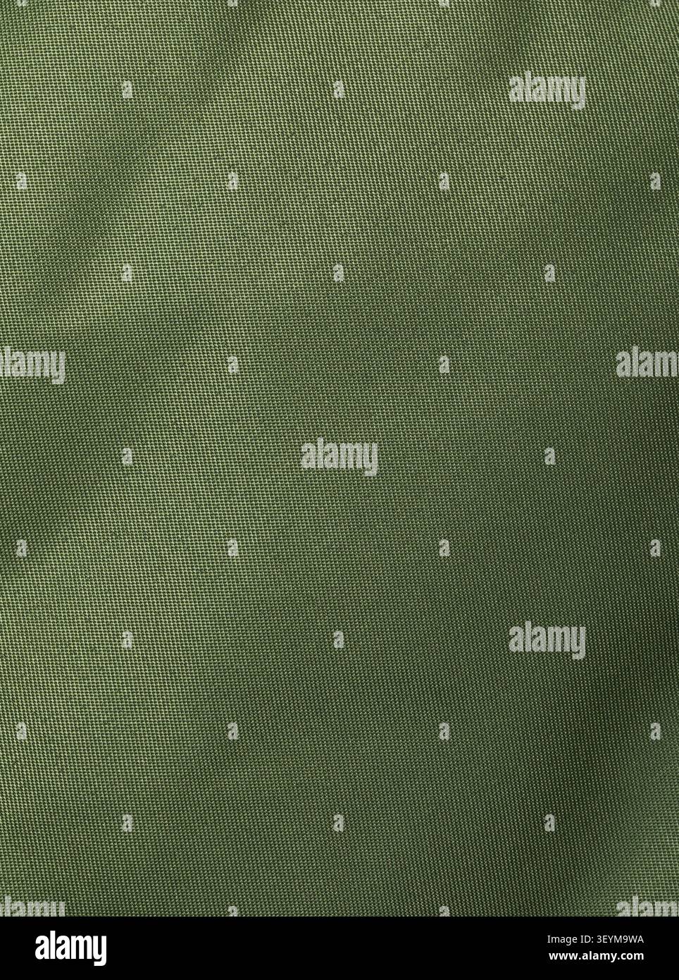 Dense synthetic olive khaki fabric texture with fine plain weave and soft folds, close-up background Stock Photo