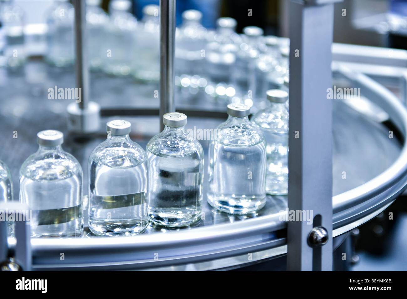 Biotechnology factory conveyor line transporting clear vaccine liquid glass containers Stock Photo
