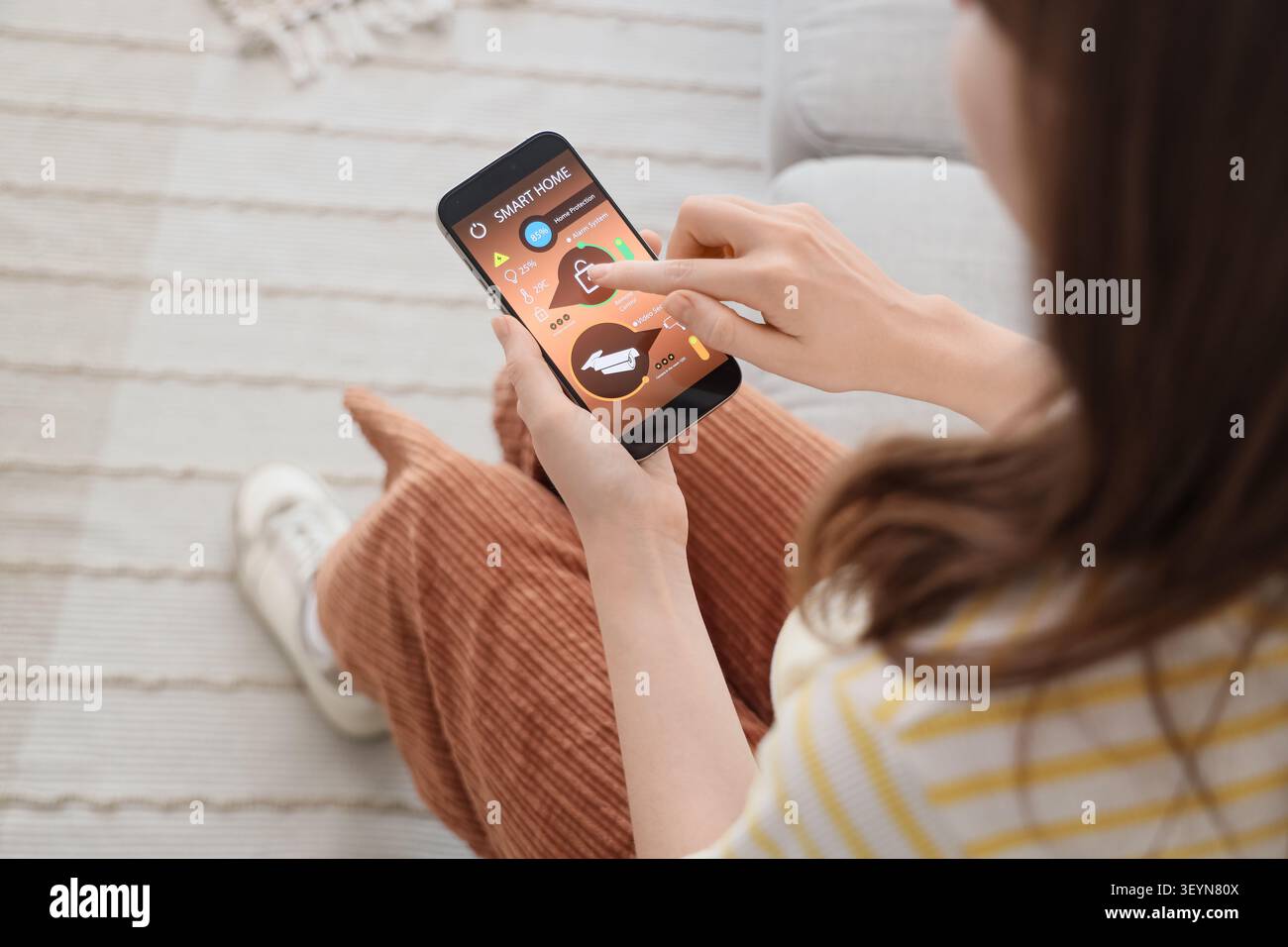 Woman using smartphone smart home security app Stock Photo