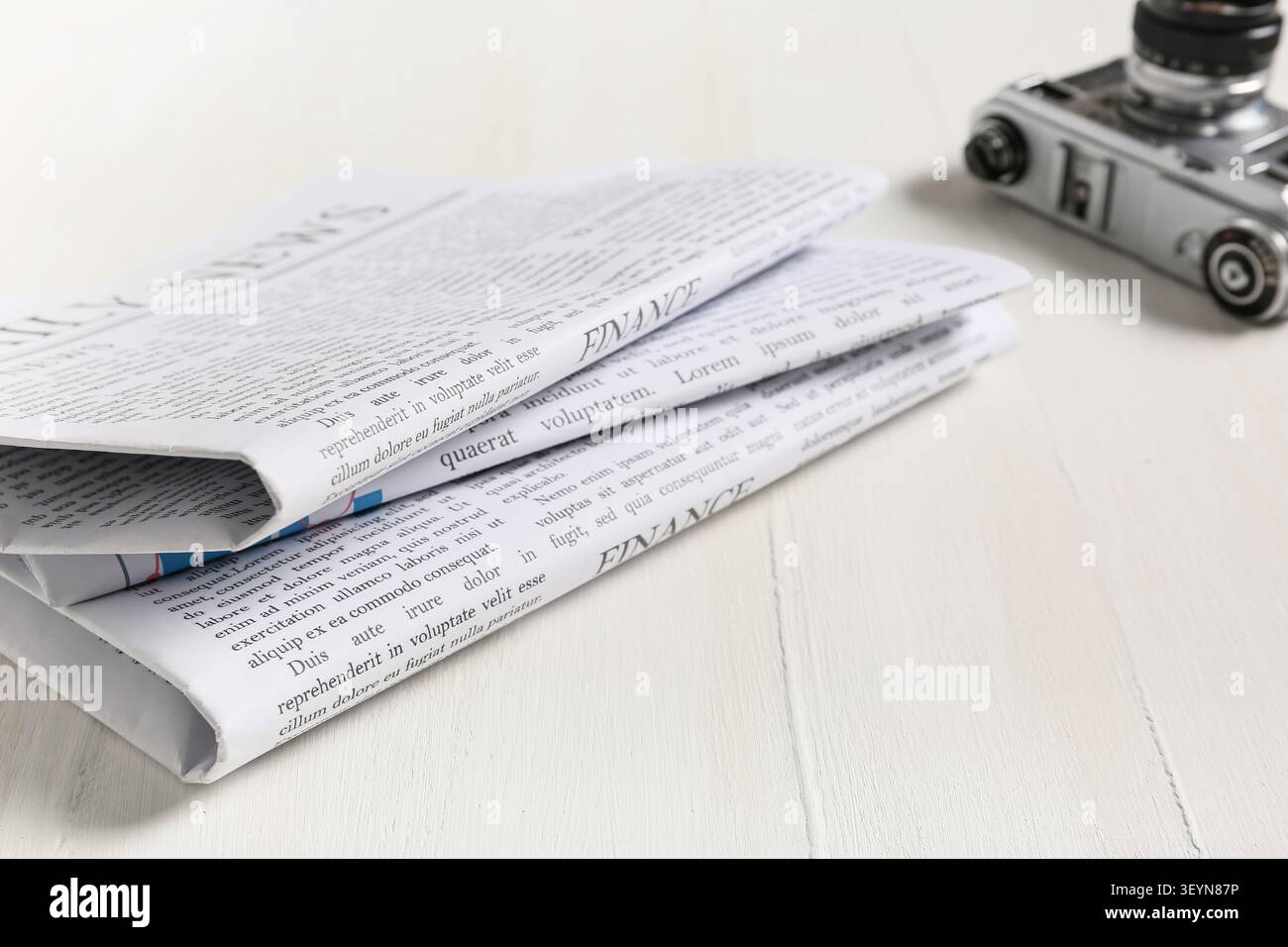 Folded newspapers on white wooden table with vintage camera Stock Photo