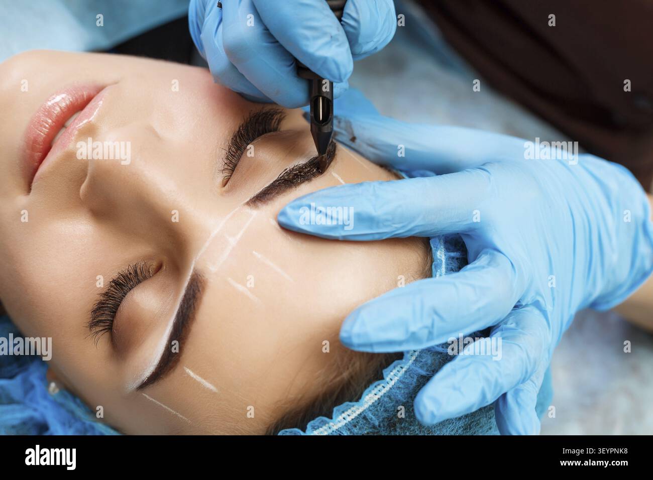 Cosmetologist applying permanent make up on eyebrows- eyebrow tattoo Stock Photo