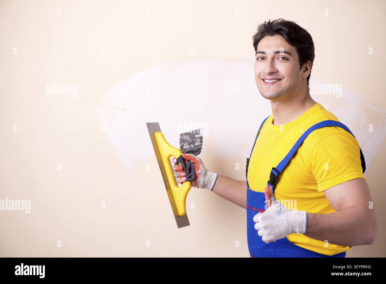Young contractor employee applying plaster on wall Stock Photo