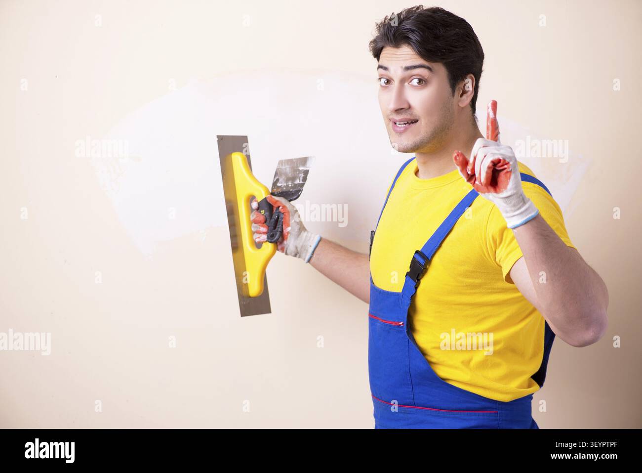 Young contractor employee applying plaster on wall Stock Photo
