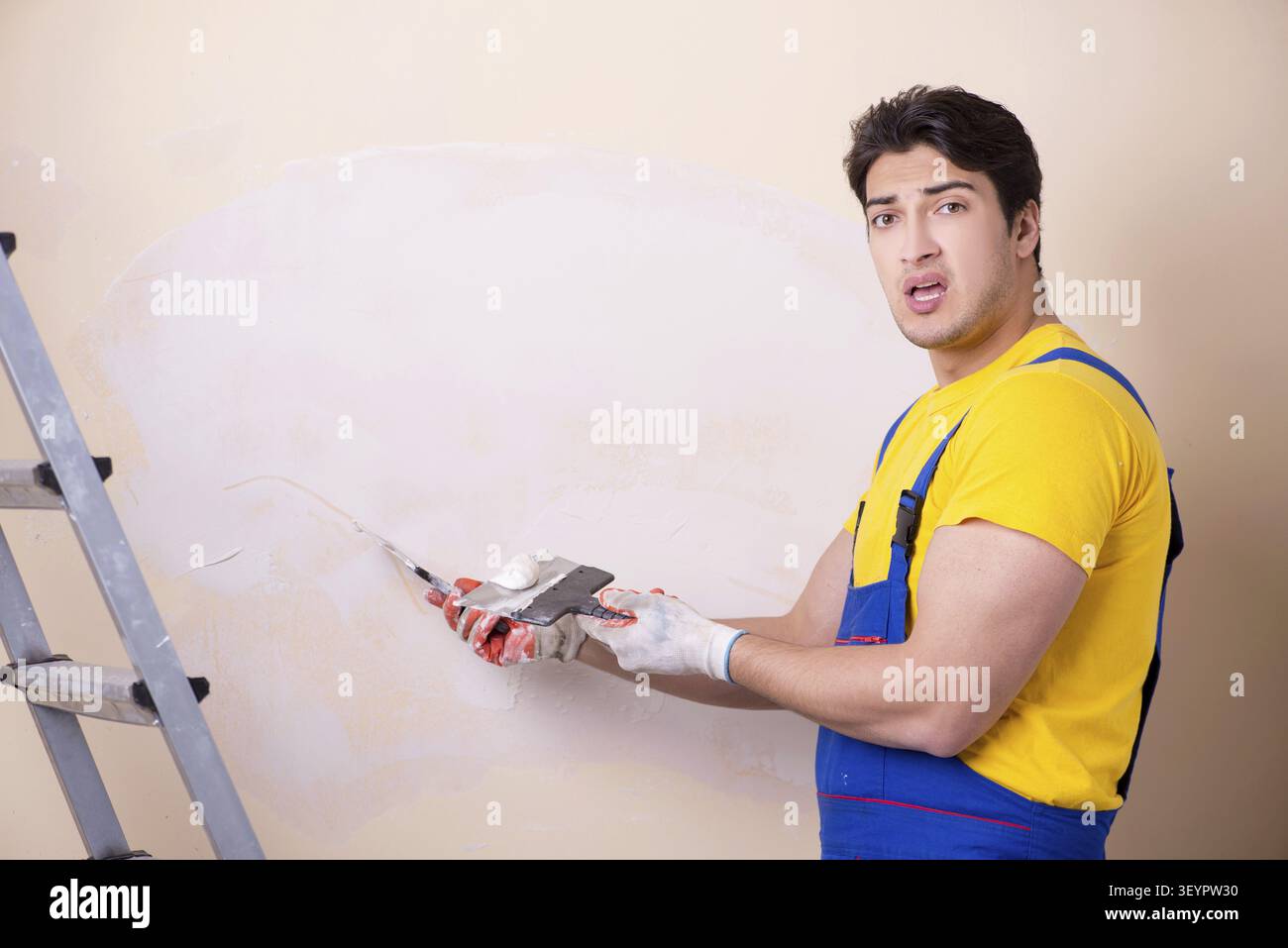 Young contractor employee applying plaster on wall Stock Photo
