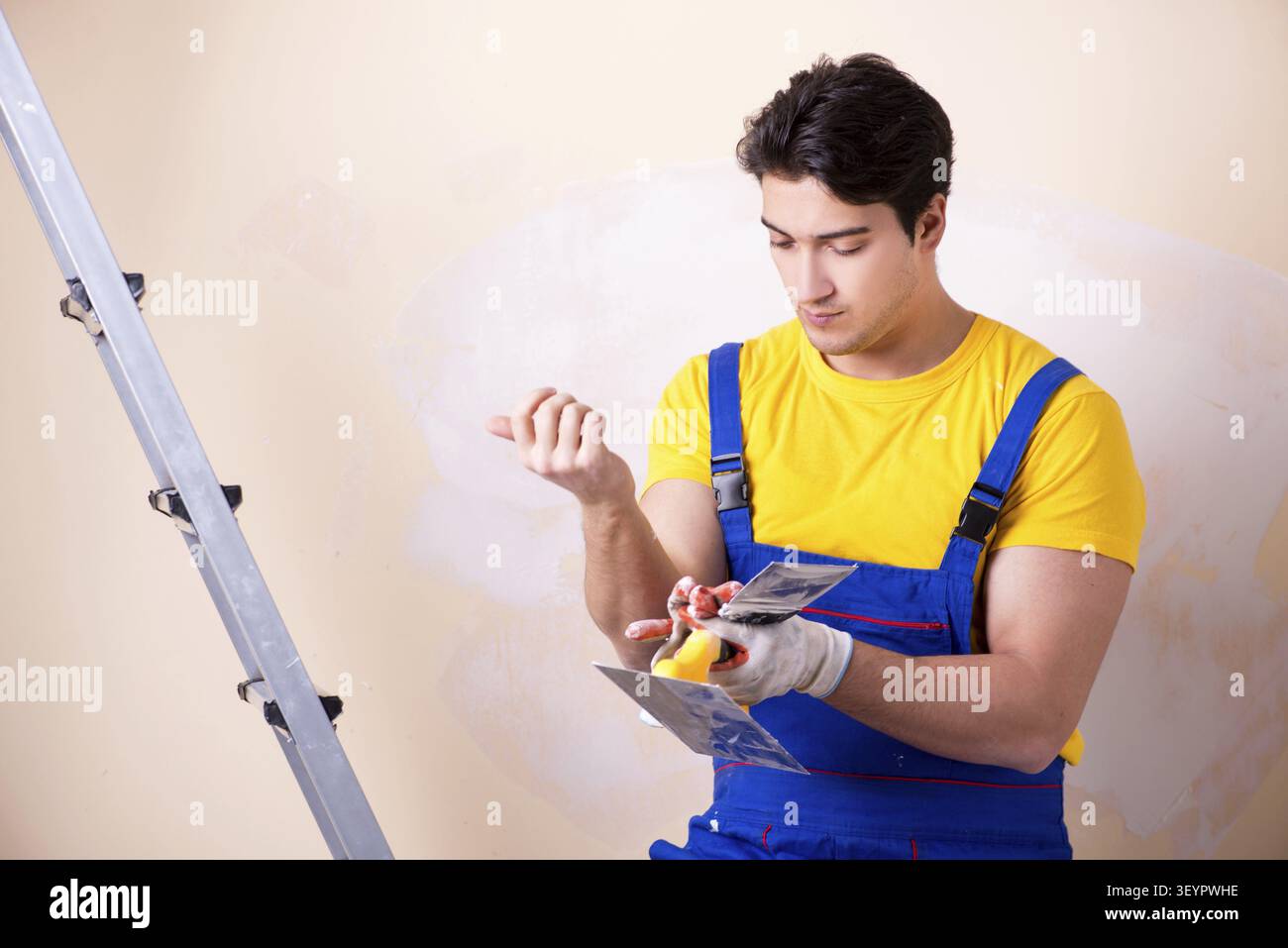 Young contractor employee applying plaster on wall Stock Photo