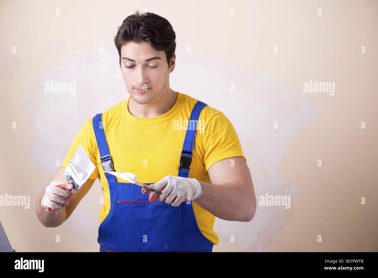 Young contractor employee applying plaster on wall Stock Photo