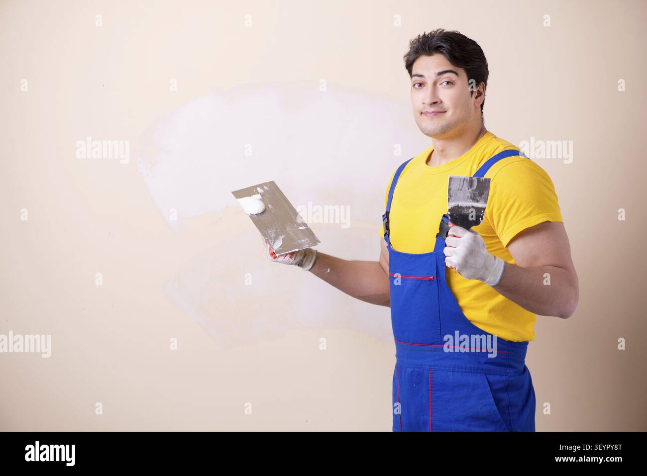 Young contractor employee applying plaster on wall Stock Photo