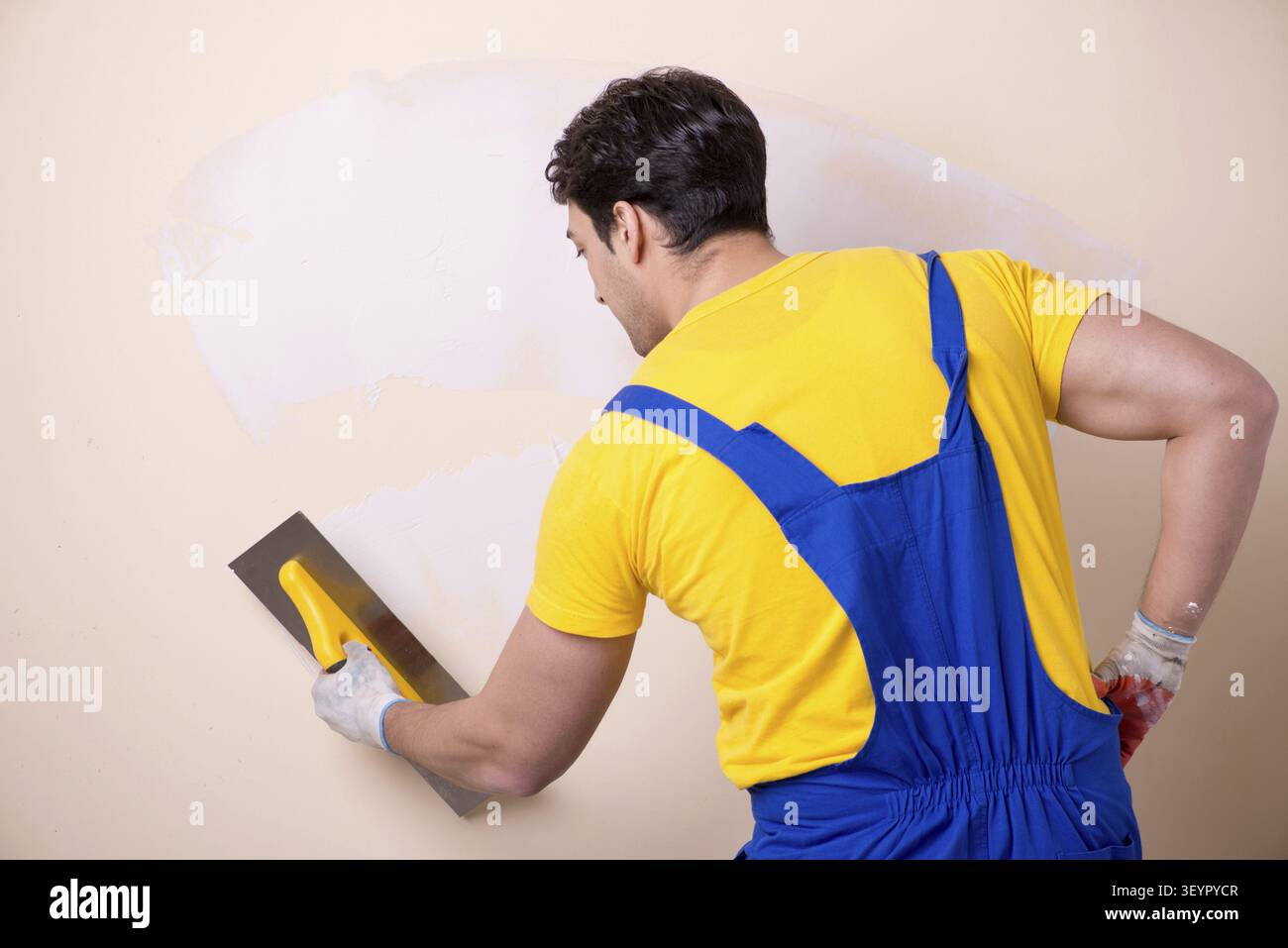 Young contractor employee applying plaster on wall Stock Photo