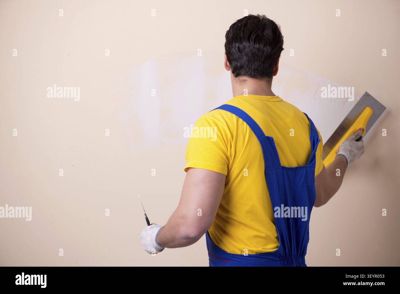 Young contractor employee applying plaster on wall Stock Photo