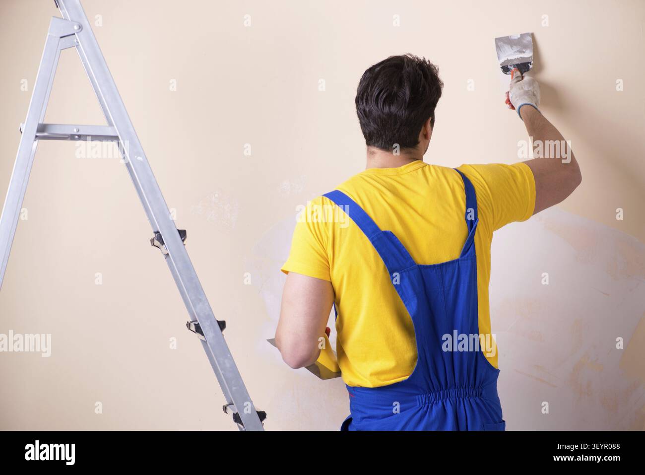 Young contractor employee applying plaster on wall Stock Photo