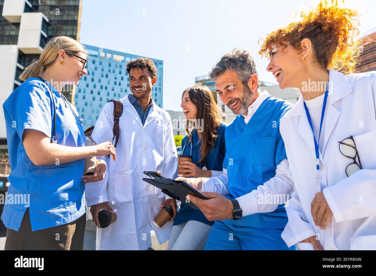 Diverse medical staff team discussing health concepts outdoors Stock Photo