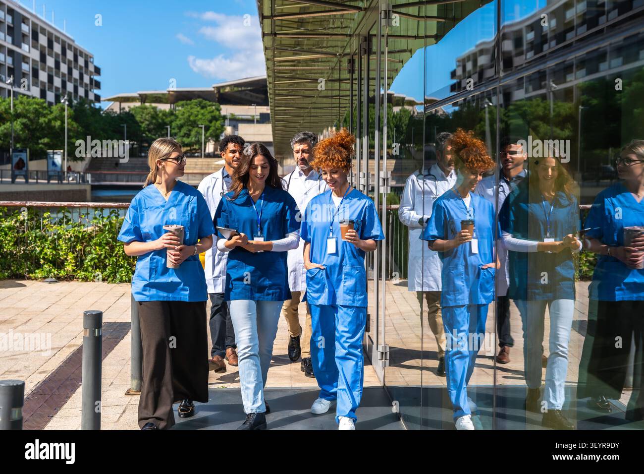 Diverse medical team walking together outside hospital building Stock Photo