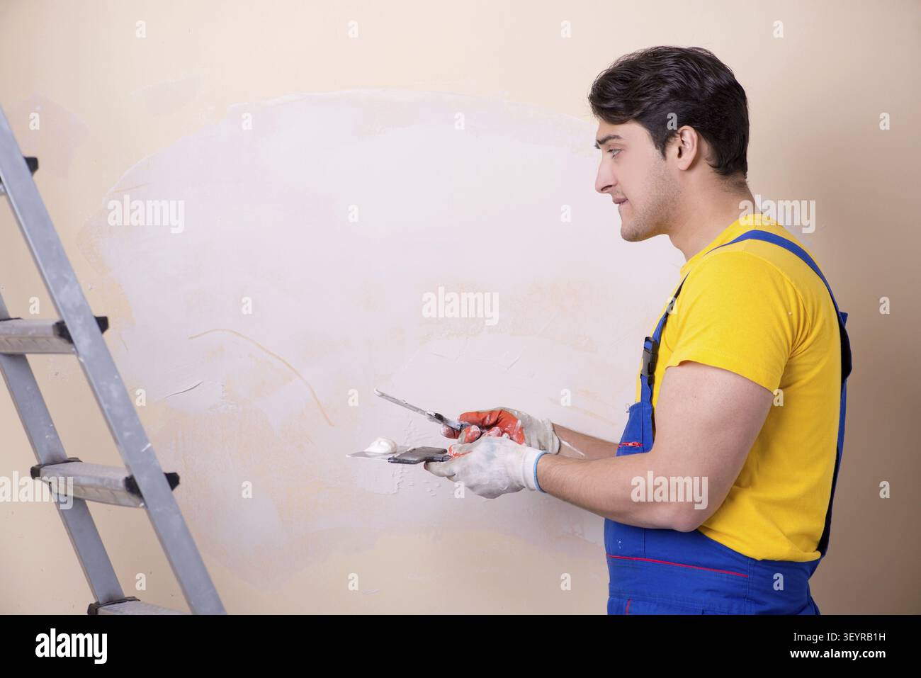 Young contractor employee applying plaster on wall Stock Photo