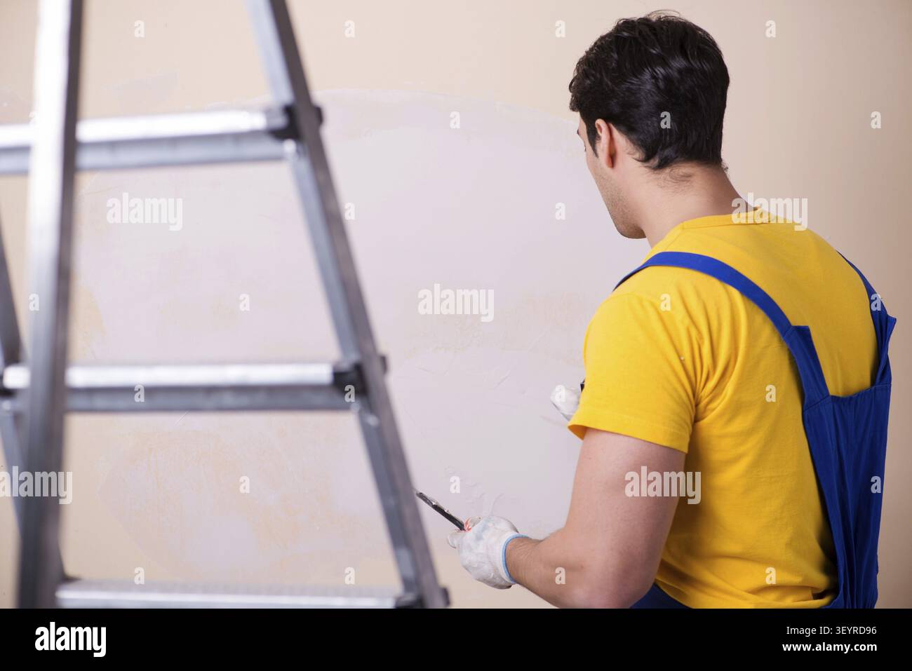 Young contractor employee applying plaster on wall Stock Photo