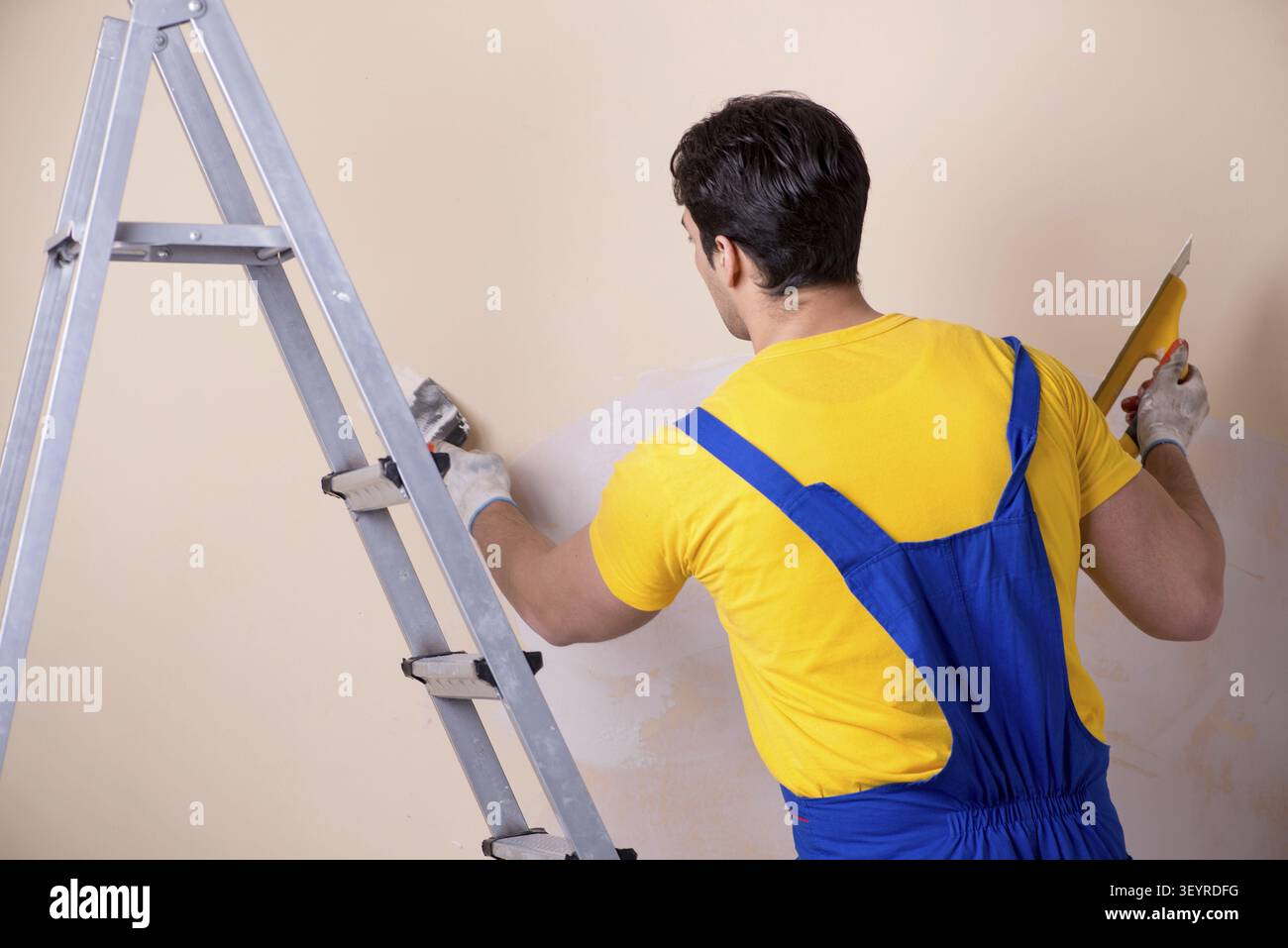 Young contractor employee applying plaster on wall Stock Photo