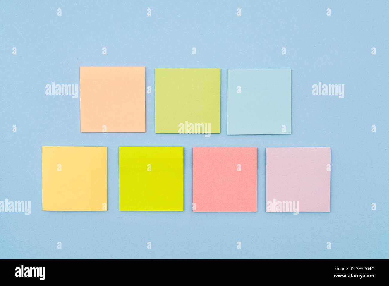 Seven colorful sticky notes are arranged in two rows on a blue background. The top row has three notes, and the bottom row has four. Stock Photo