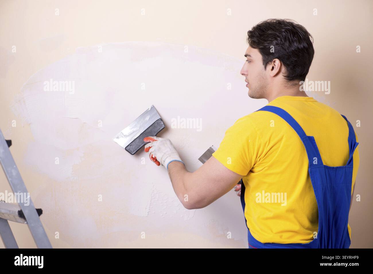 Young contractor employee applying plaster on wall Stock Photo