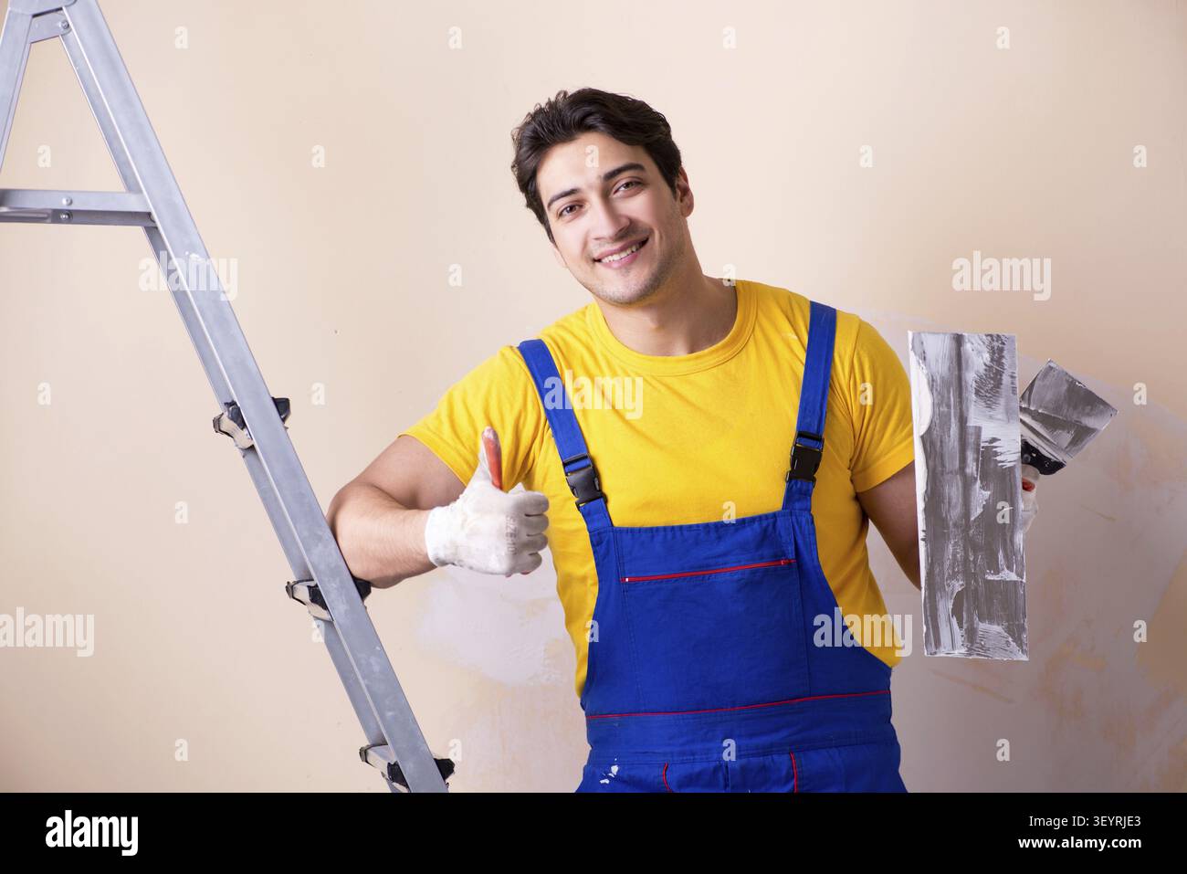 Young contractor employee applying plaster on wall Stock Photo
