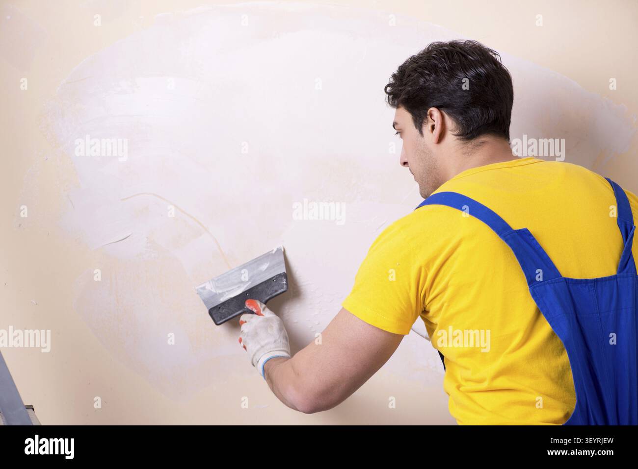 Young contractor employee applying plaster on wall Stock Photo