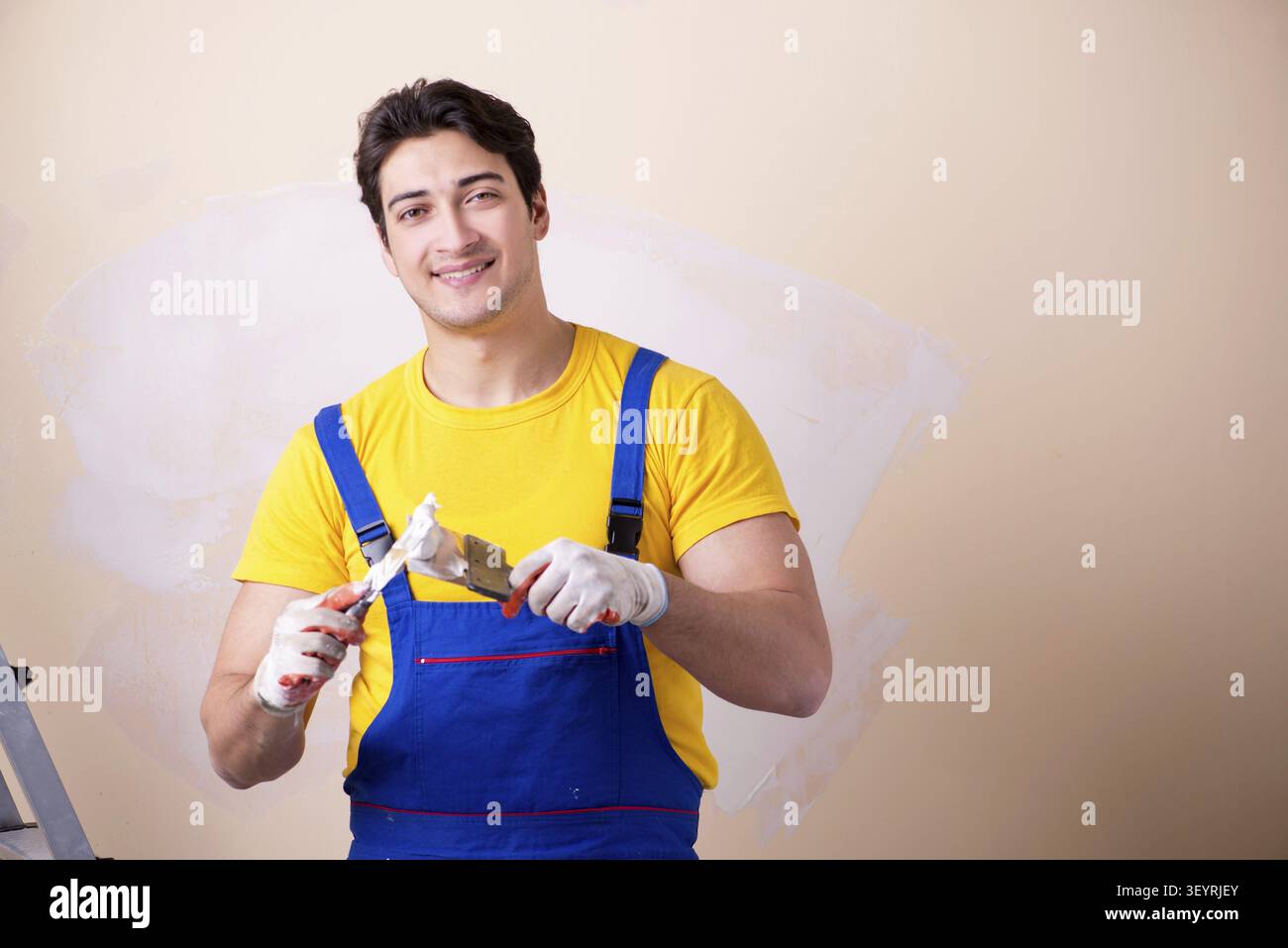 Young contractor employee applying plaster on wall Stock Photo