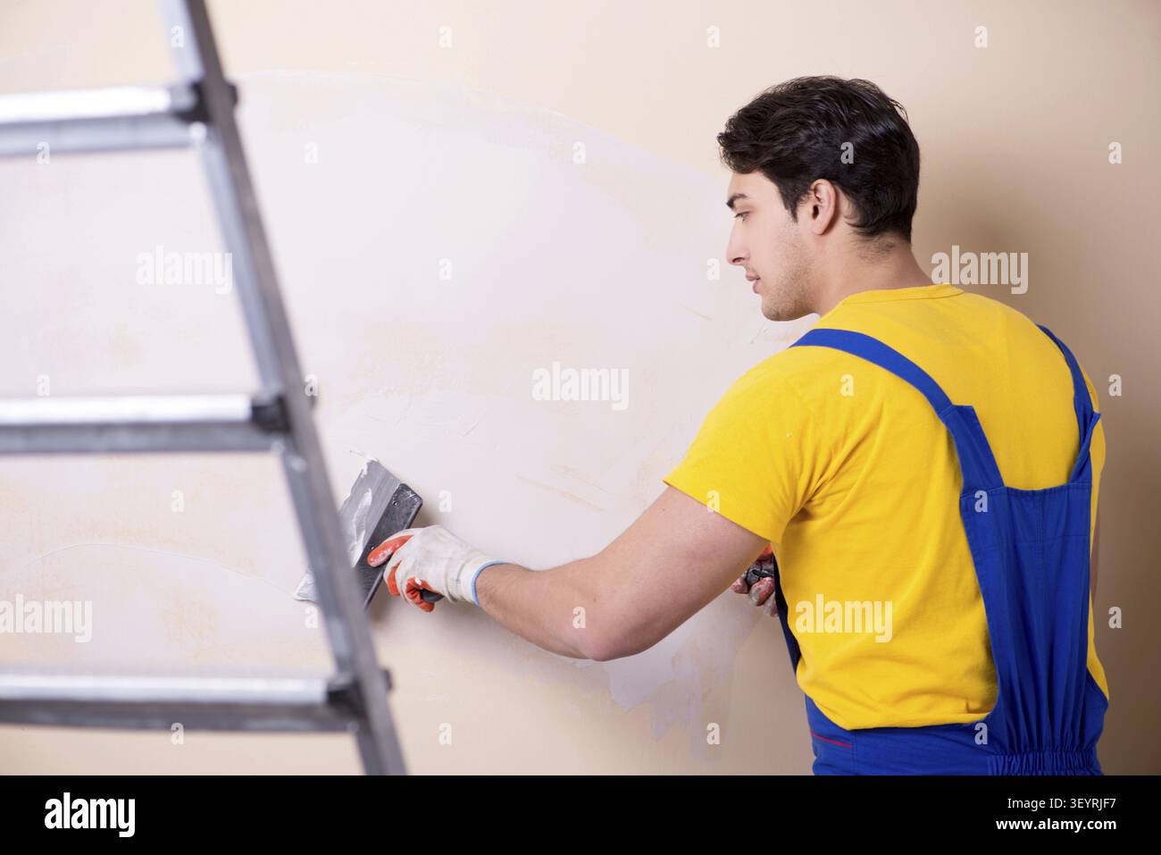 Young contractor employee applying plaster on wall Stock Photo