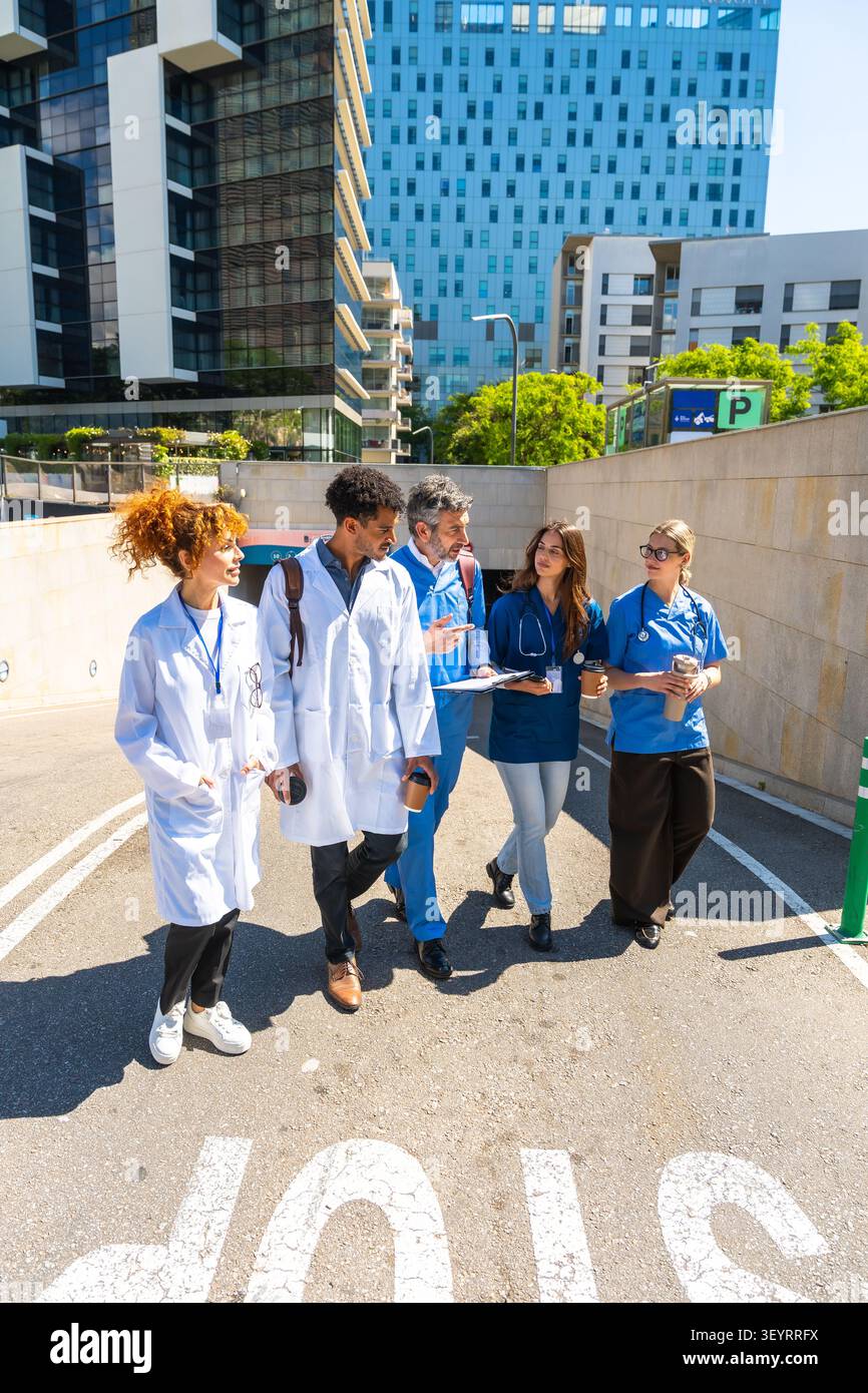 Diverse medical staff walking discussing healthcare in urban setting Stock Photo