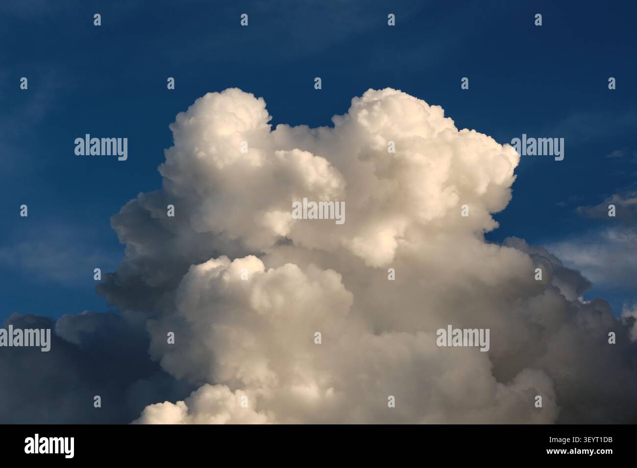 Beautiful large cumulus cloud structure glowing under sunlight against deep blue sky backdrop Stock Photo