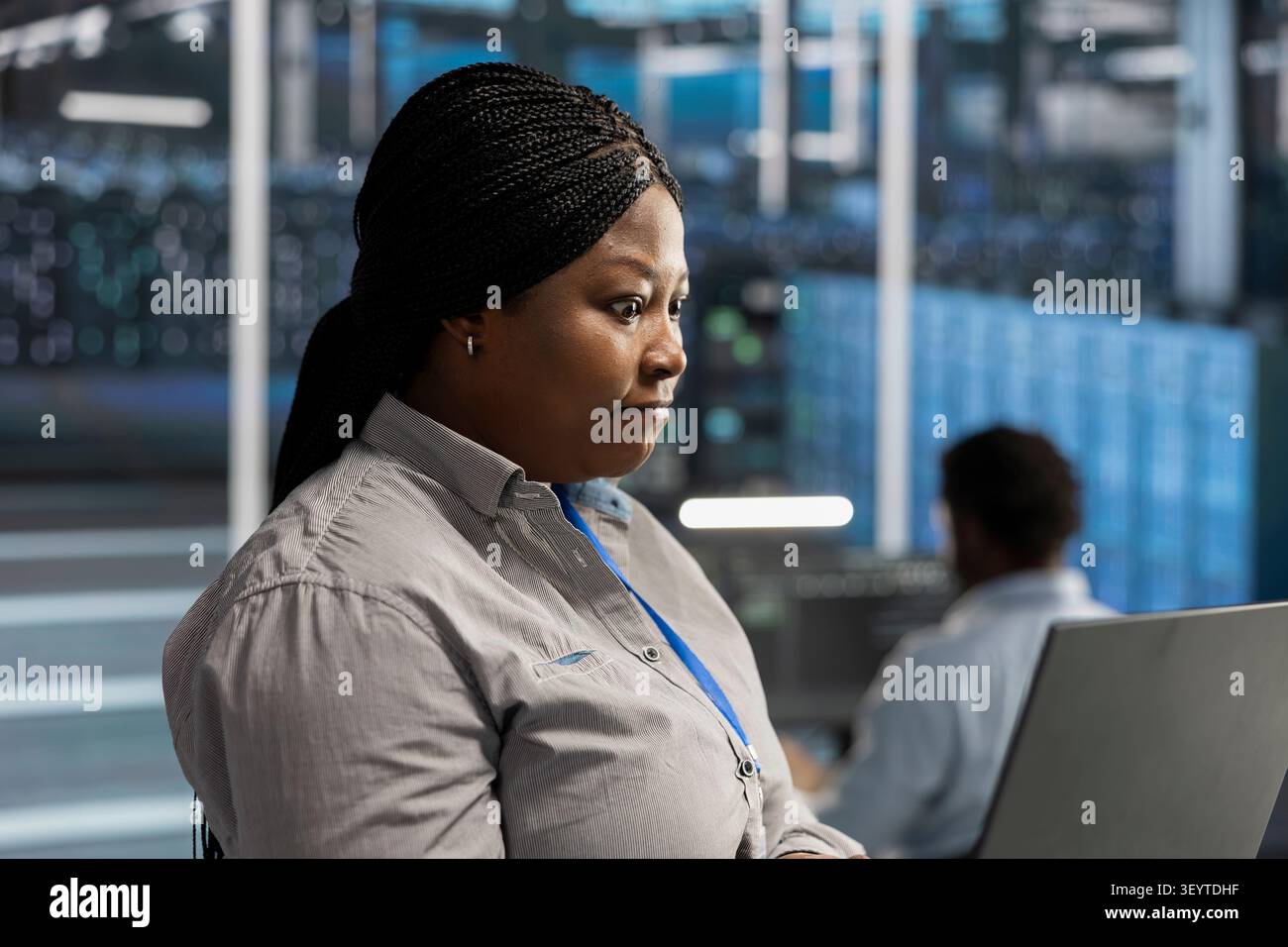 African American engineer uses a notebook to oversee data center machines, maintain server rigs and solve complex workloads. Stock Photo