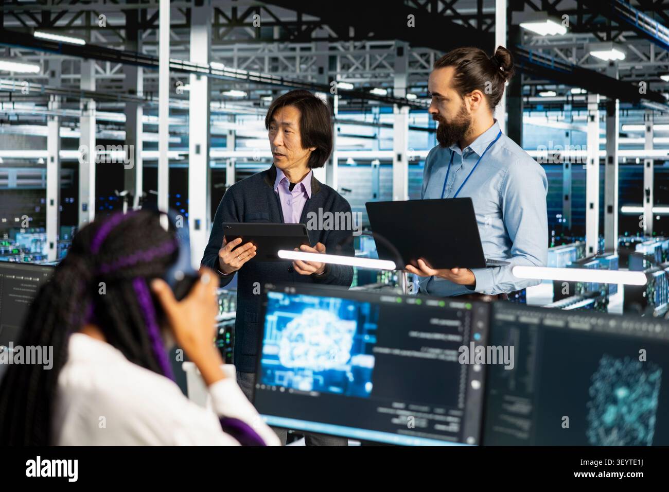 Data center colleagues collaborate on coding and AI automation scripts while reviewing server infrastructure together. Stock Photo
