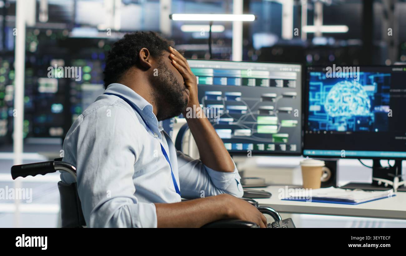 Engineer using a wheelchair reacts to a slow AI node tree tool while working in a data center. Stock Photo